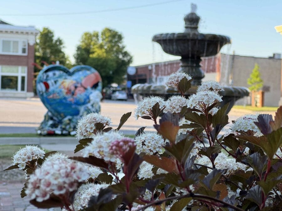 Elms Blvd fountain with the Parade of Hearts statue on display near 10 Highway; flowers in the foreground