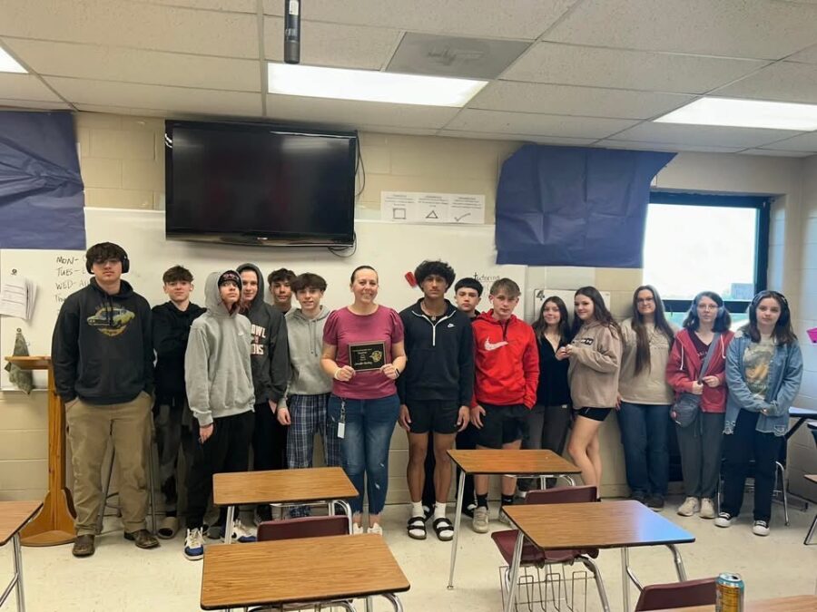 Harding and her students smile together while holding her Teacher of the Year award.